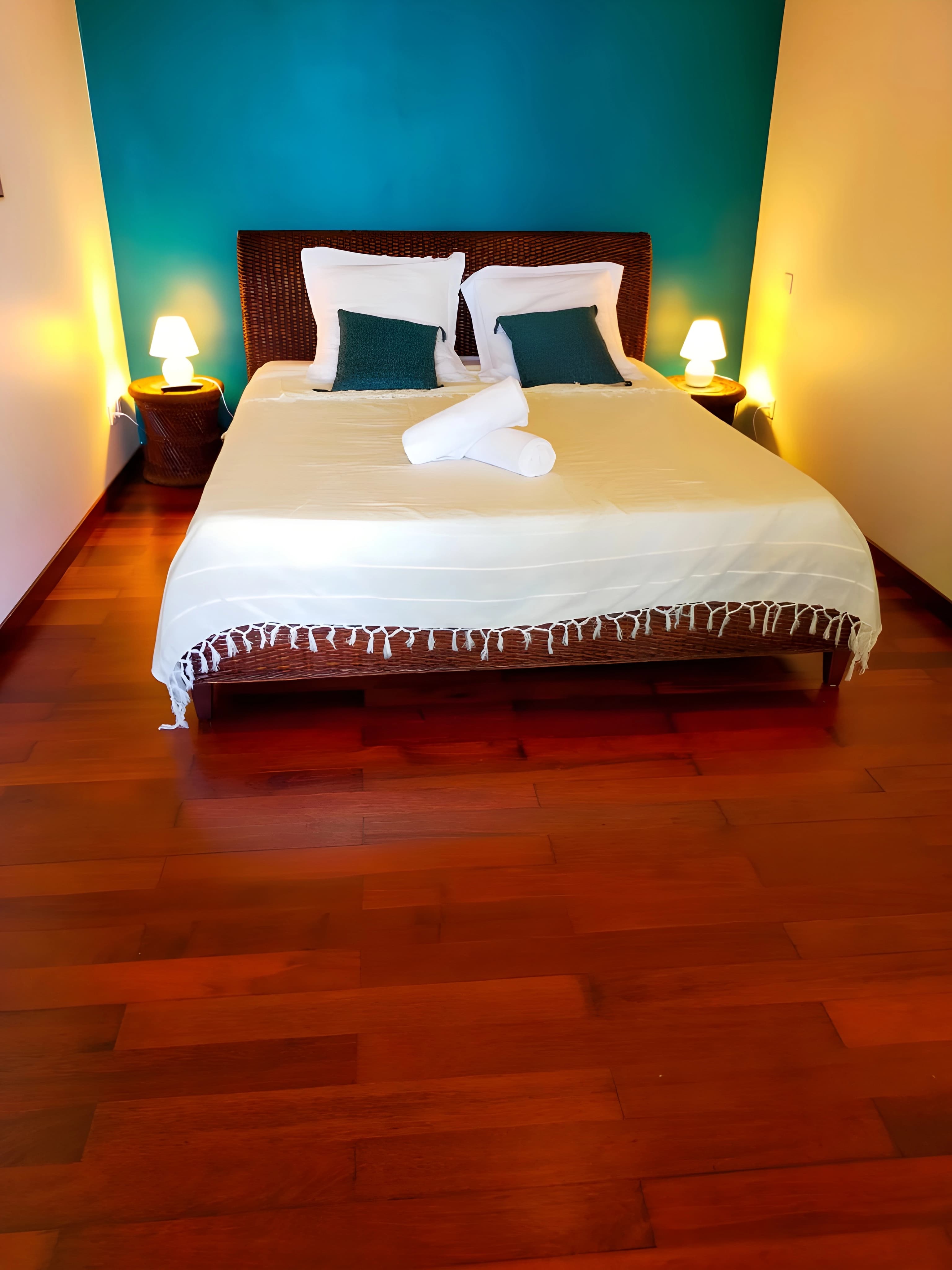 Chambre du studio indépendant, lit double et parquet, mur turquoise